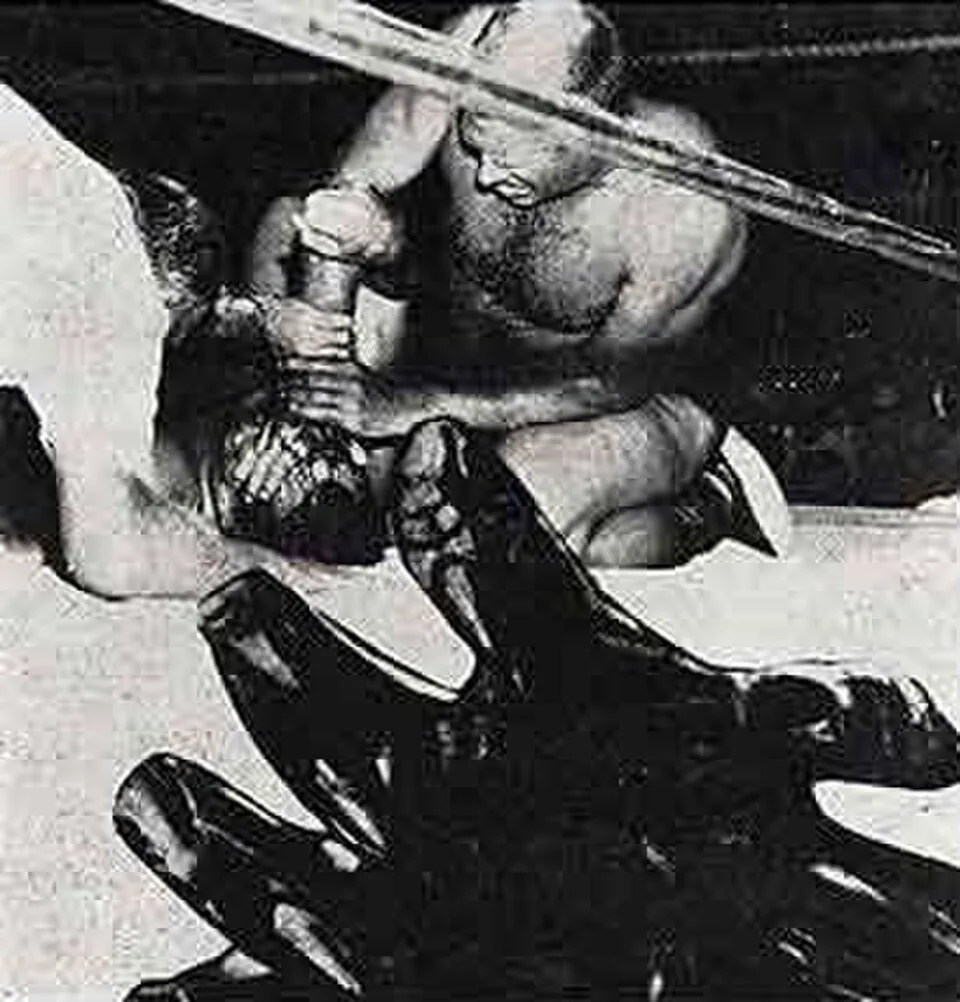 Fritz Von Erich applying the Iron Claw in a 1977 wrestling program photograph