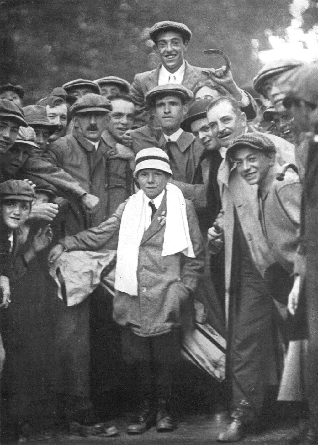 Francis Ouimet carried by spectators, September 1913. Caddie Eddie Lowery is in the foreground with a towel around his neck. Near the top center, Ouimet is raised above a dense crowd. Lowery stands in the lower center with a light-colored towel around his neck. Spectators around him wear varied hats.