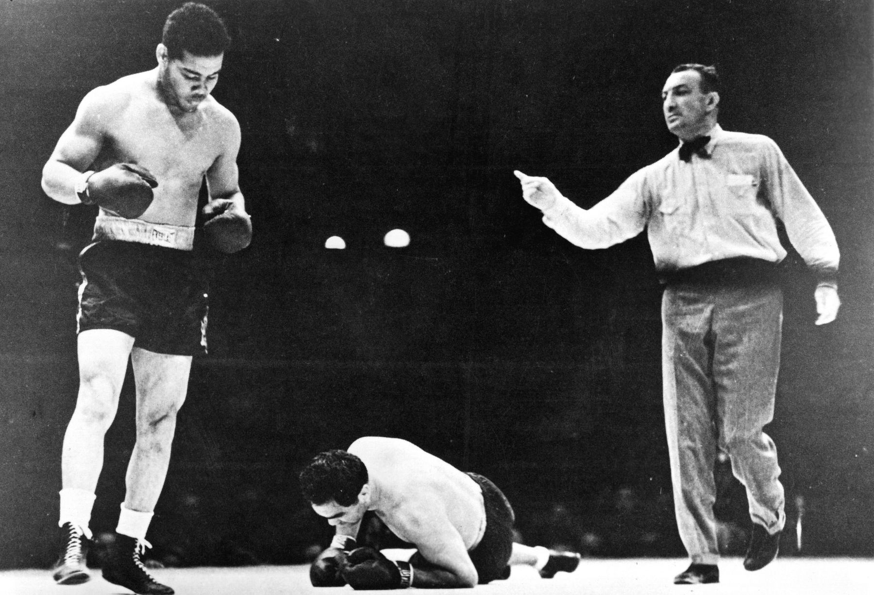 Joe Louis walking away as Max Schmeling kneels on the canvas, June 22, 1938