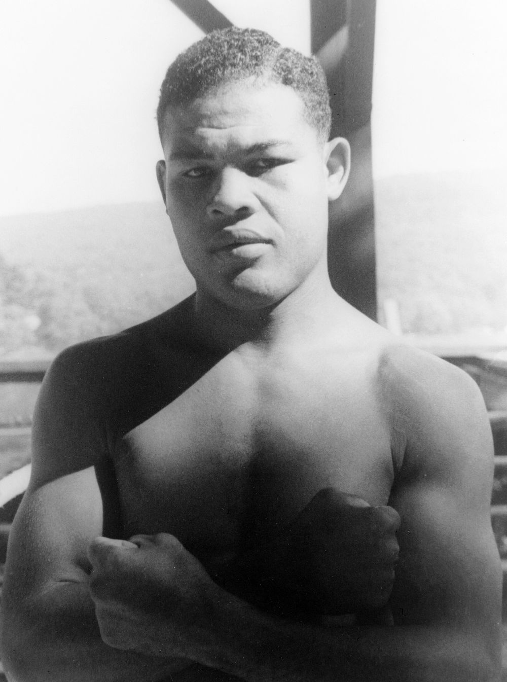 Joe Louis, shirtless, arms folded, looking straight at the camera.