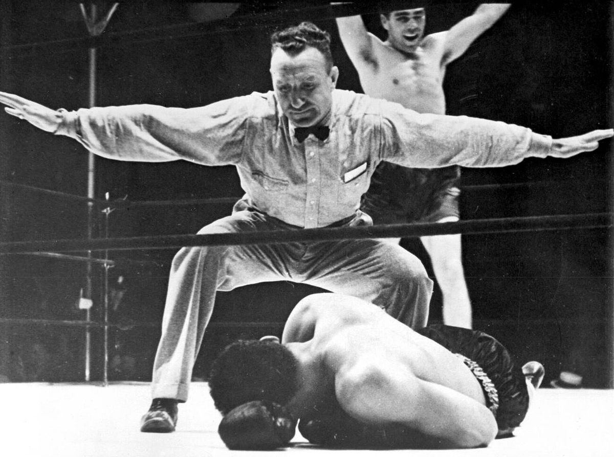 Referee counting over Joe Louis, who lies face down on the canvas while Schmeling raises his arms.
