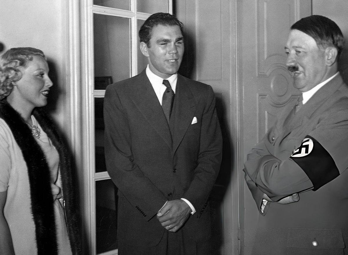 Max Schmeling in a suit beside his wife Anny Ondra, facing Adolf Hitler, who wears a swastika armband.