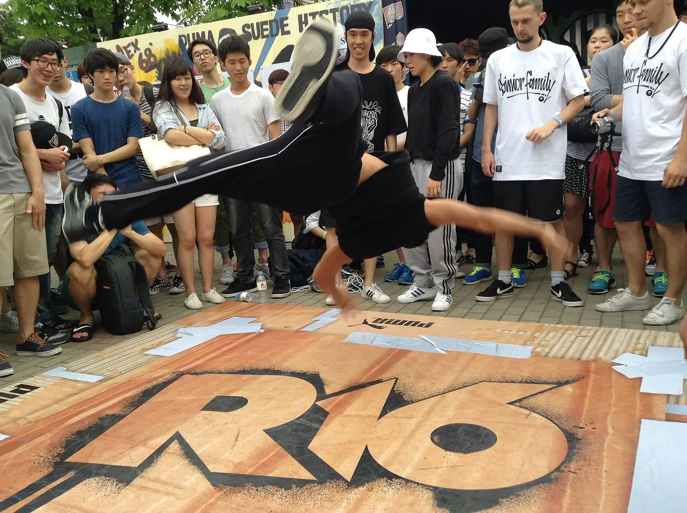 A breaker spinning on one hand inside a crowded street cypher in Seoul
