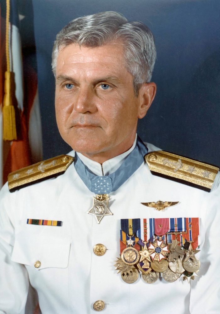 Formal portrait of James Stockdale in a white Navy dress uniform with rows of medals.