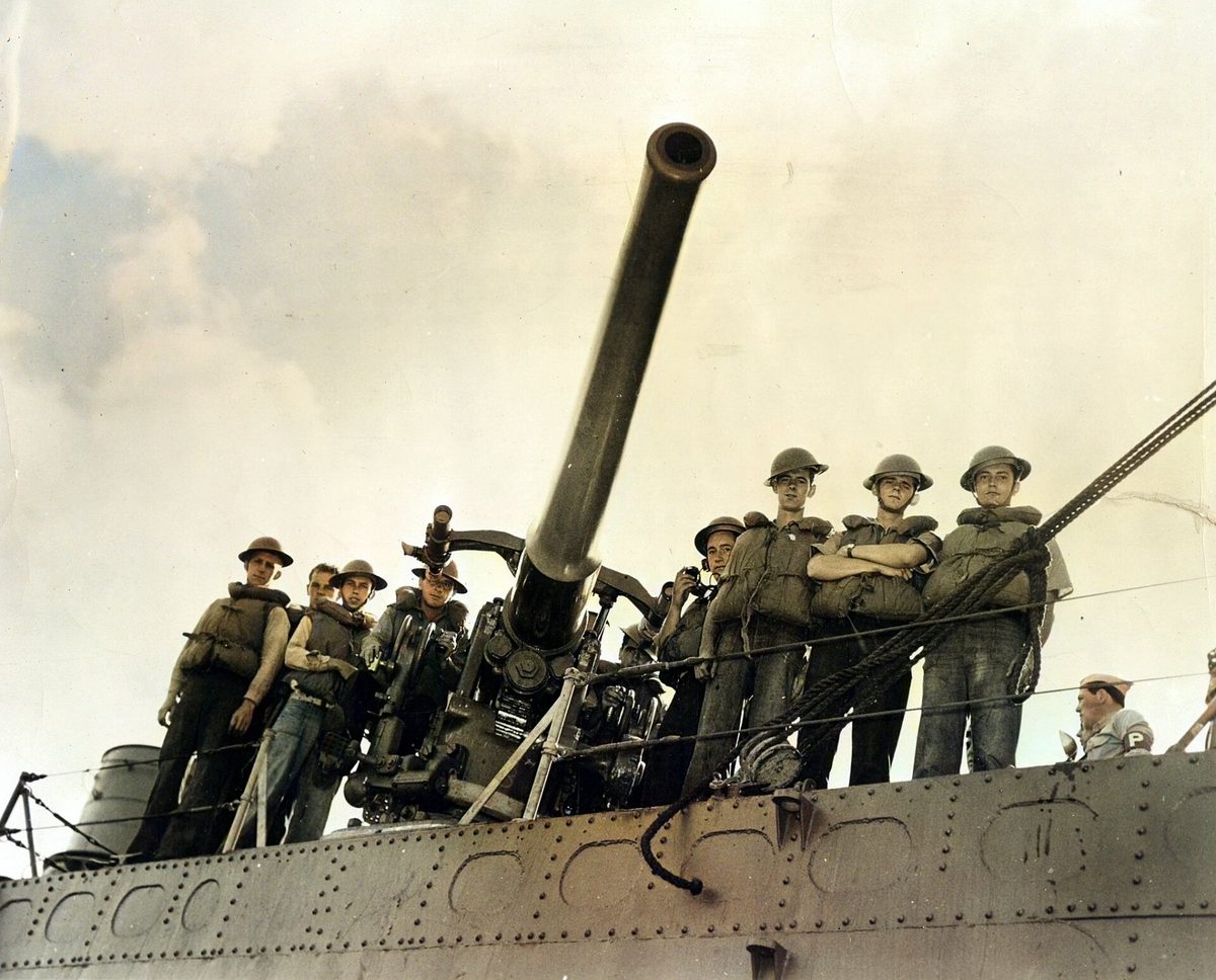 Sailors in helmets and life jackets standing around a deck gun on the destroyer Ward.