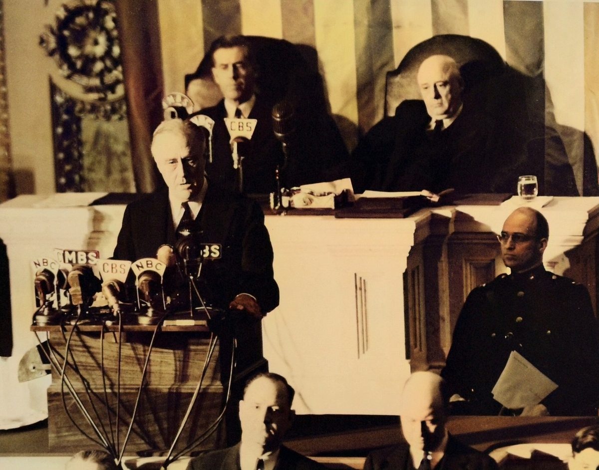 President Roosevelt speaking at a rostrum covered with radio microphones before Congress.
