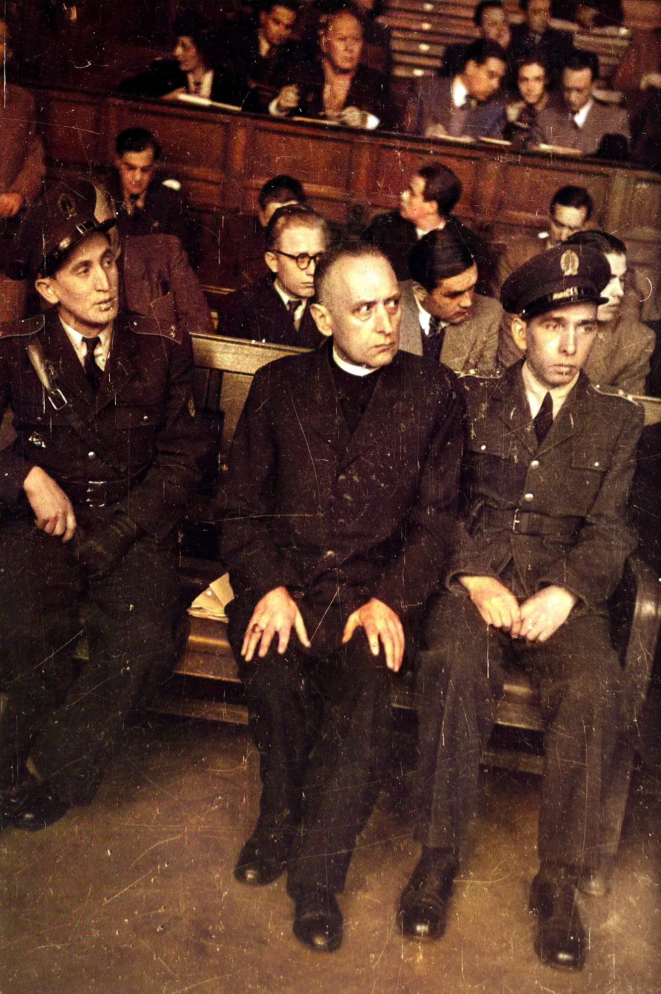Cardinal Jozsef Mindszenty seated between uniformed guards in a crowded Budapest courtroom, 1949