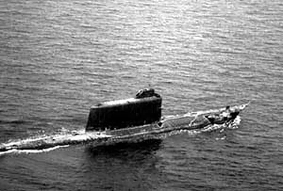 A long black Soviet submarine running on the surface, its tall sail in the middle