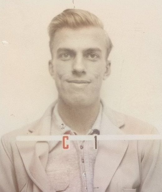Security badge portrait of a young man with light hair in a pale jacket.