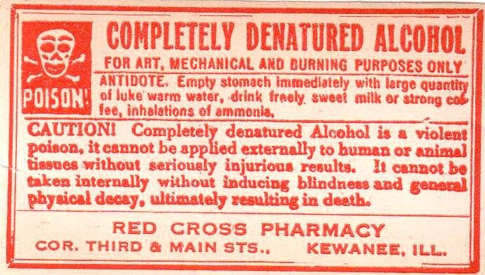 A red and white pharmacy label headed Completely Denatured Alcohol, with a skull and crossbones and the word Poison, warning that it cannot be taken internally without inducing blindness.