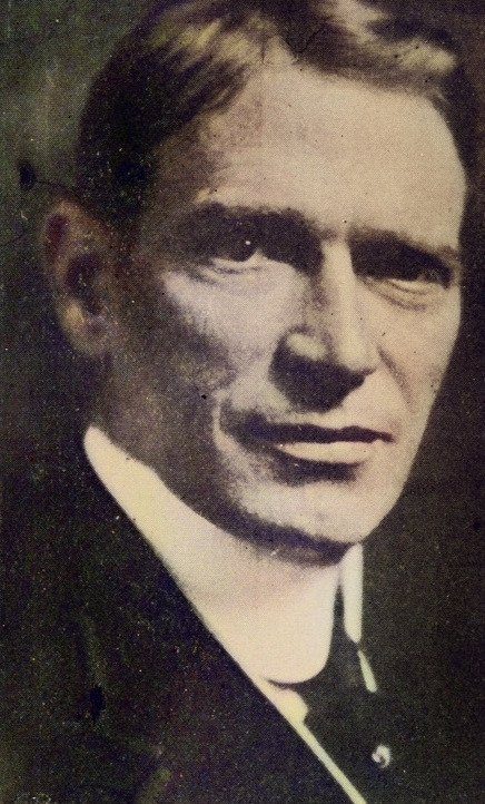 Close portrait of a man with a strong jaw in a high collar.