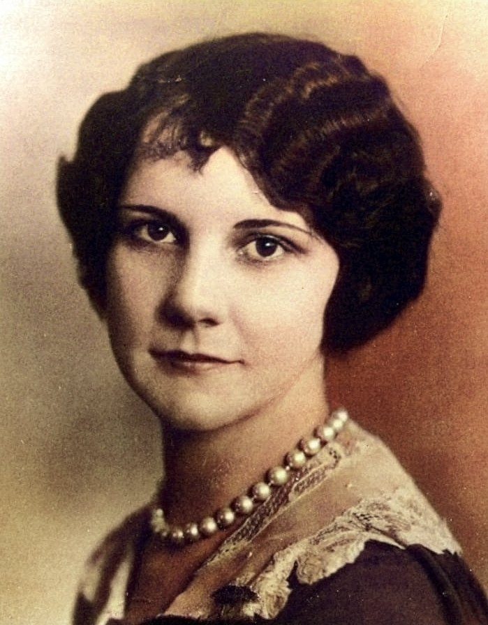Portrait of a young woman with short dark waved hair and a pearl necklace.
