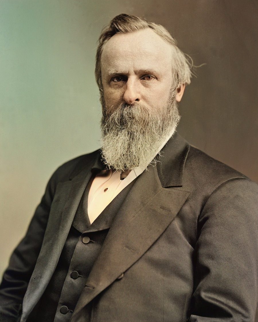 Colorized portrait of Rutherford B. Hayes with a long full beard and a dark suit
