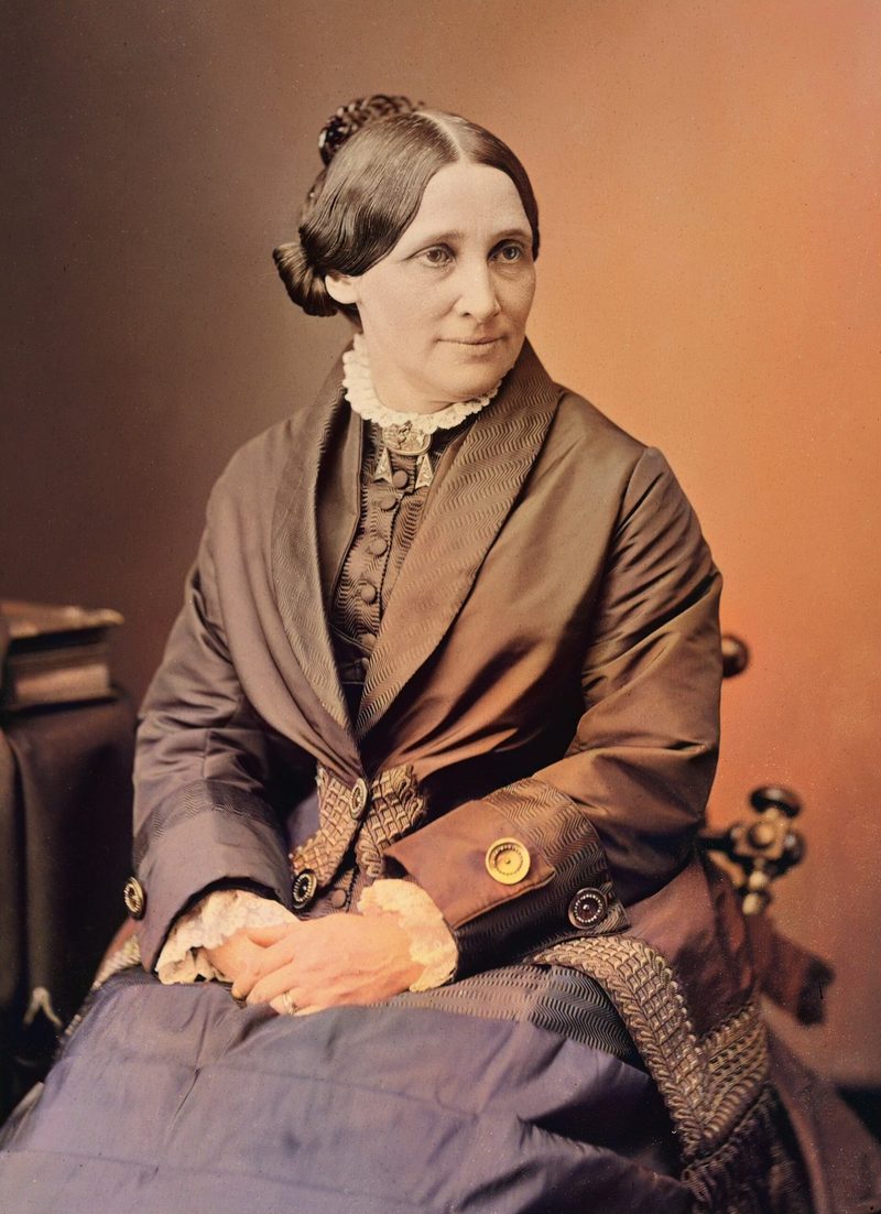 Colorized portrait of Lucy Webb Hayes, seated, hair parted in the middle and pulled back, in a dark silk dress with a lace collar